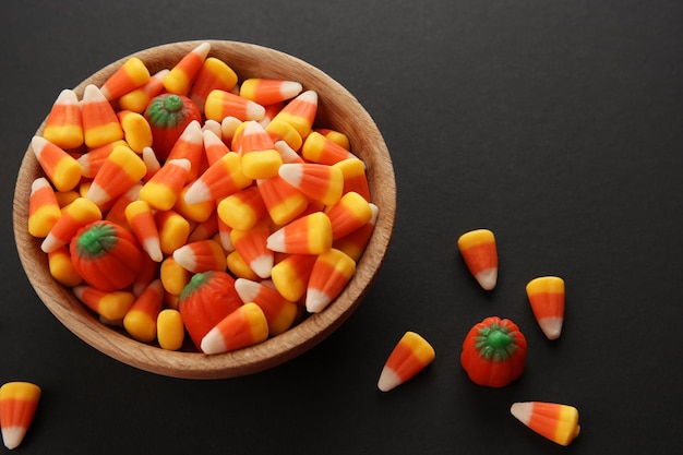 Bowl with tasty Halloween candies on dark background