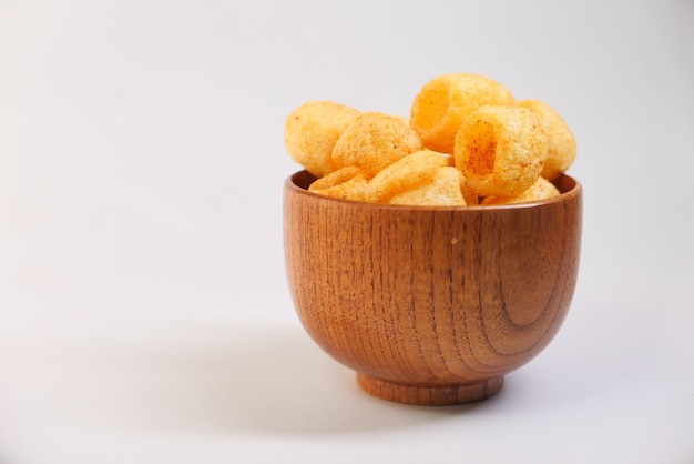 Bowl with tasty potato chips on white background .