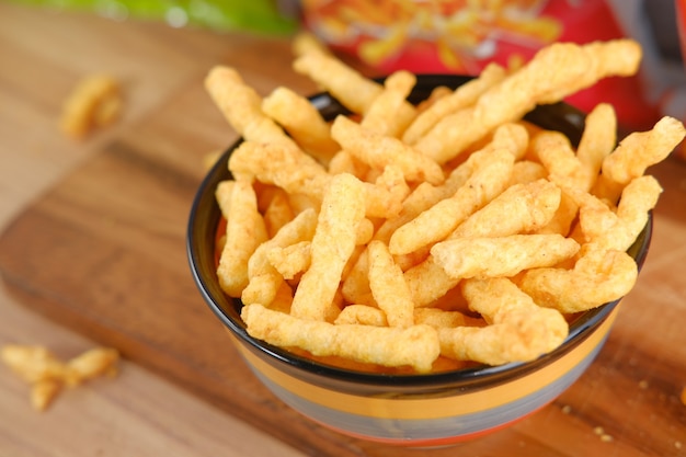 Bowl with tasty potato chips on wooden