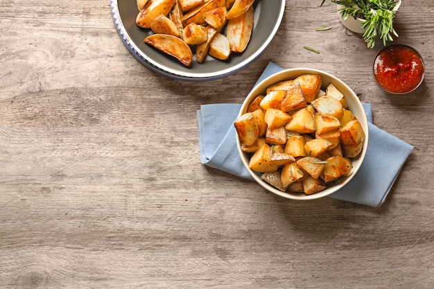 Bowl with tasty potato wedges on table