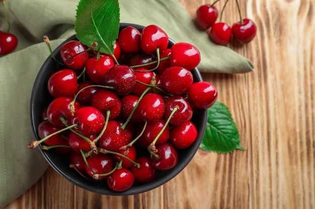 Bowl with tasty ripe cherries on wooden table