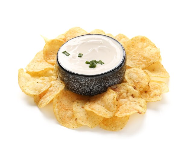 Bowl with tasty sour cream and potato chips on white