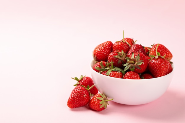 분홍색 배경에 맛있는 딸기와 그릇. 여름 베리