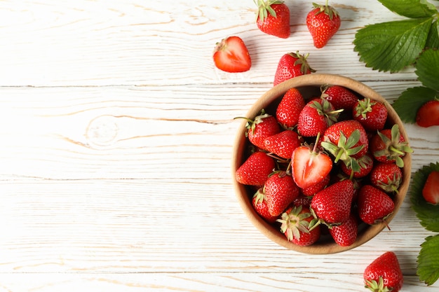 Bowl with tasty strawberry on wooden table. Summer berry