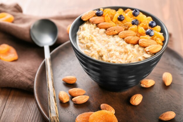 Bowl with tasty sweet oatmeal on table