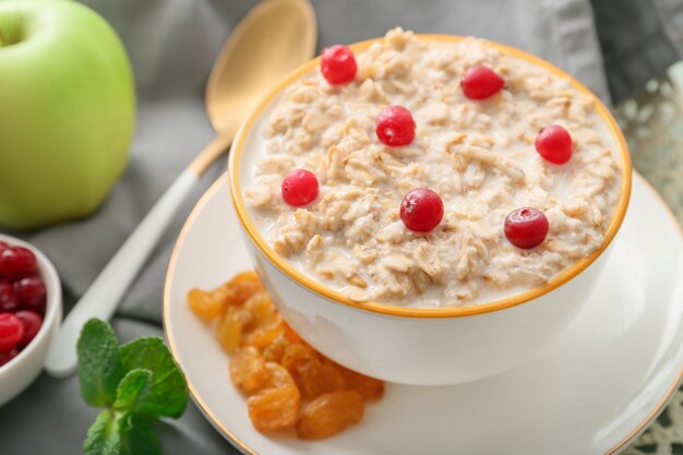 Bowl with tasty sweet oatmeal on tray, closeup