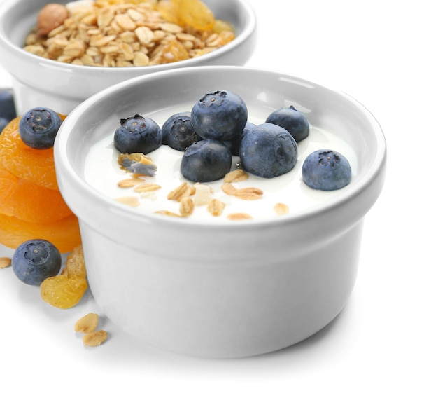 Bowl with tasty yogurt flakes and berries on white background closeup