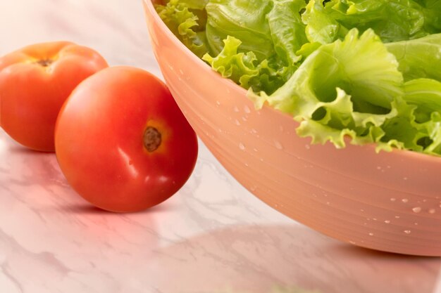 Photo bowl with tomato and lettuce salad on wooden background