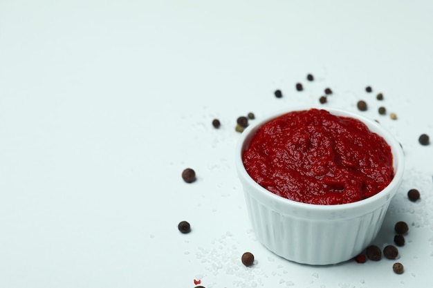 Bowl with tomato paste, pepper and salt on white surface