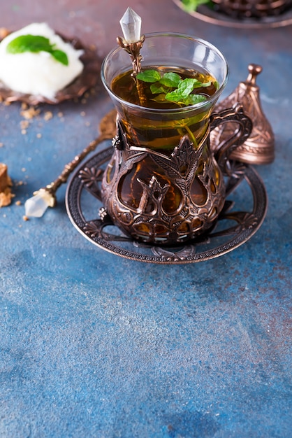 Bowl with Turkish cotton candy Pismaniye and black tea with mint on a dark,