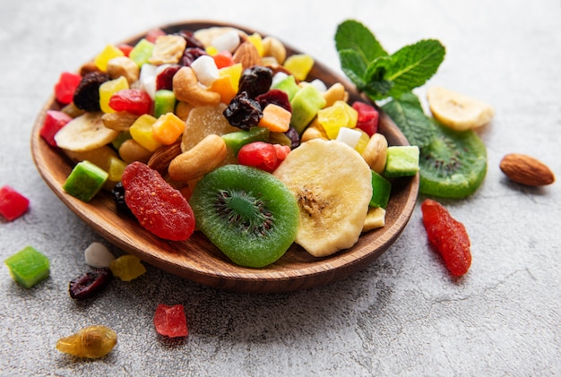 Bowl with various dried fruits and nuts on a gray concrete surface