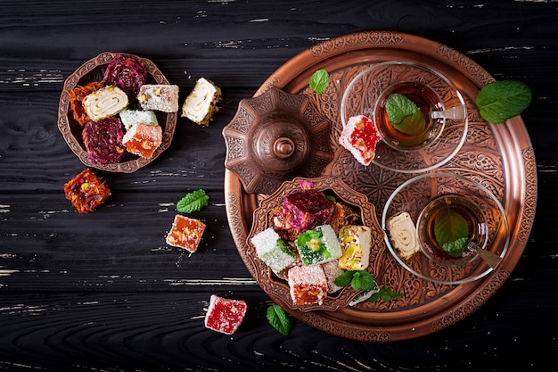 Bowl with various pieces of turkish delight lokum and black tea with mint 