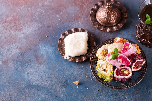 Bowl with various pieces of turkish delight lokum and black tea with mint 