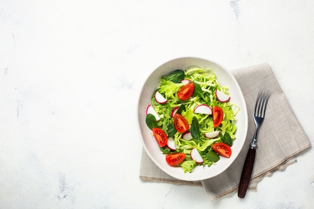 Bowl with vegetarian fresh salad. Healthy food, diet lunch. Top view on a white background.