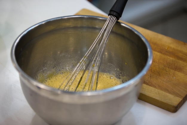 Bowl with whisk and beaten eggs