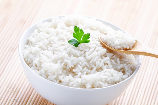 Bowl with white boiled rice with green fresh parsley for delicious healthy lunch. Cereal food and dishes.