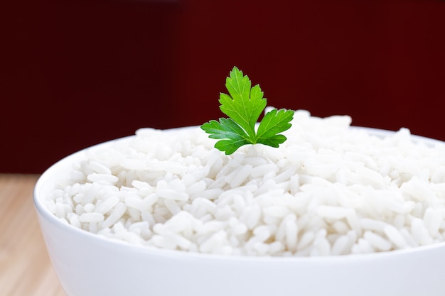 Bowl with white boiled rice with green fresh parsley for delicious healthy lunch close up.