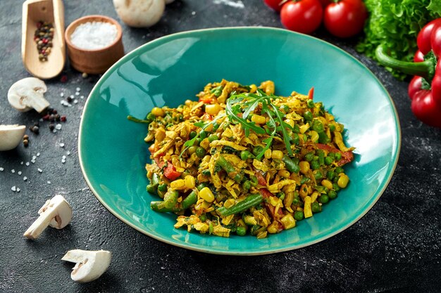 Bowl with wok fried vegetables and omelet on a black background