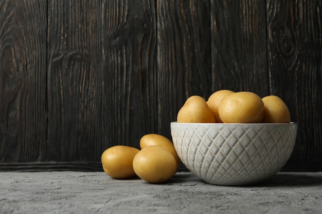 Bowl with young potatoes on grey surface