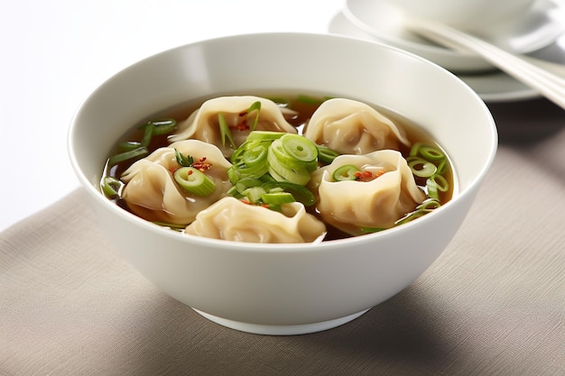 A bowl of wonton soup with green onions and scallions