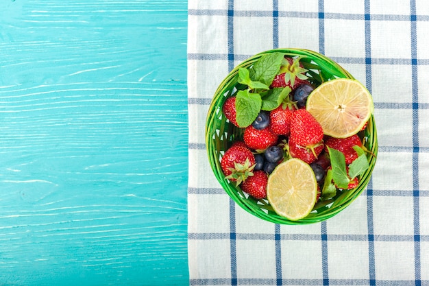 Bowl on wooden table, strawberries and blueberries inside