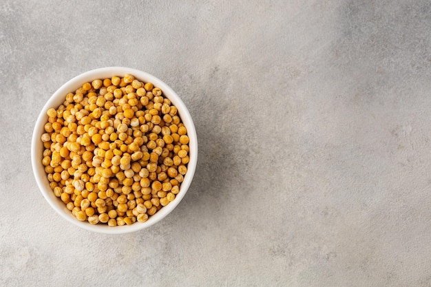 A bowl of yellow dry peas on a light background