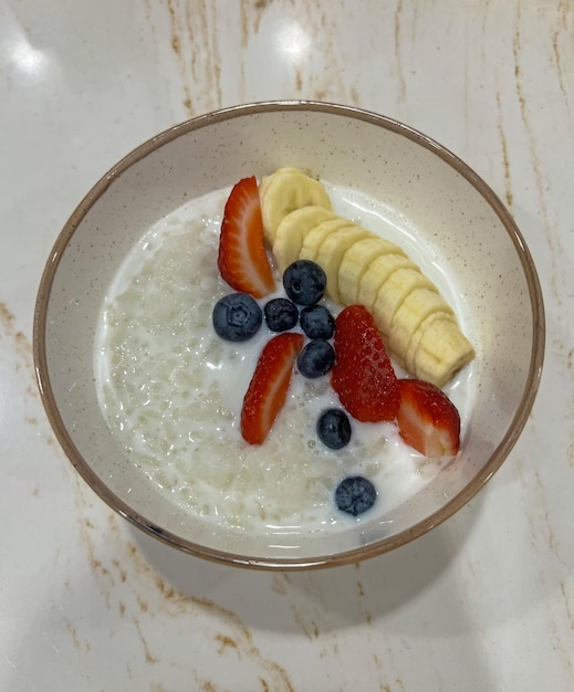 A bowl of yogurt with strawberries and blueberries in it.