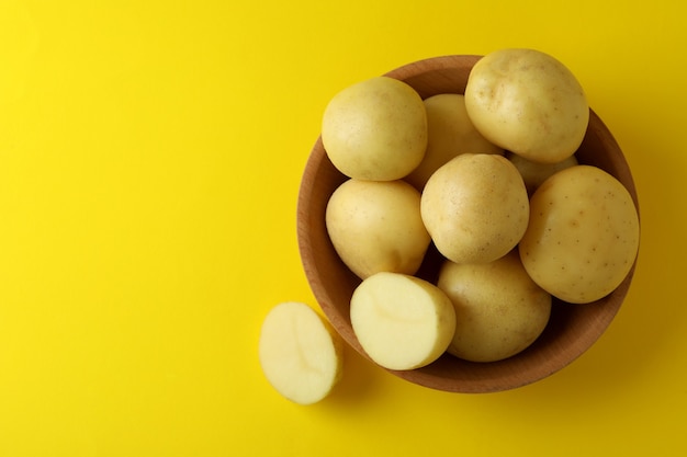 Bowl of young potato on yellow background