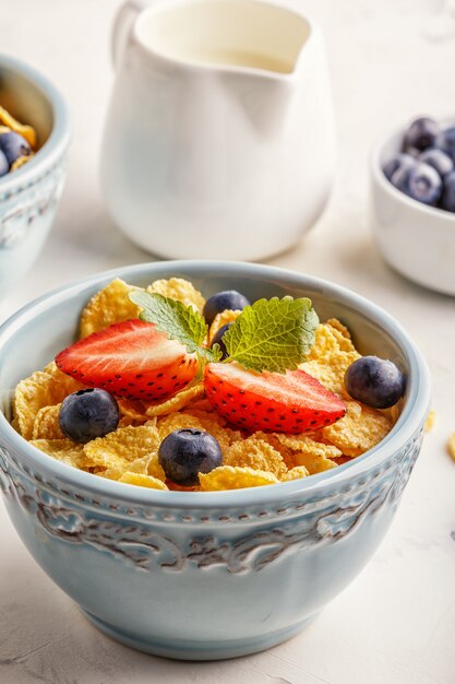 Bowls of cornflakes with strawberries and blueberries