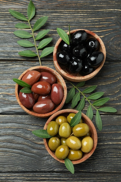 Bowls of different olives on wooden background