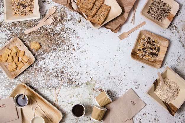 Bowls, dishes, glasses, forks, napkins and different plastic free tableware displayed around a table with different ingredients, coffe and milk