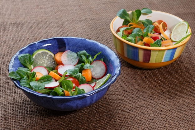 Bowls of fresh vegetable salad on jute table cloth