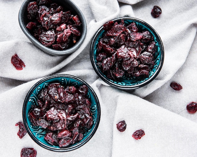 Photo bowls full of sweet dried cherries on grey textile background