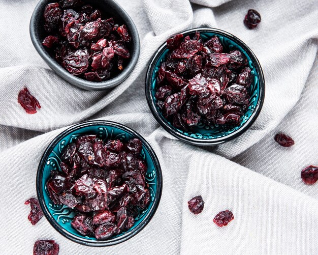 Photo bowls full of sweet dried cherries on grey textile  background