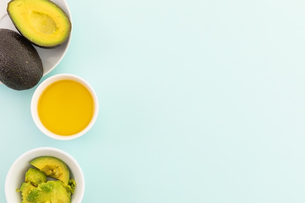 Bowls of halved avocados and dressing on blue background. fresh healthy whole food copy space concept