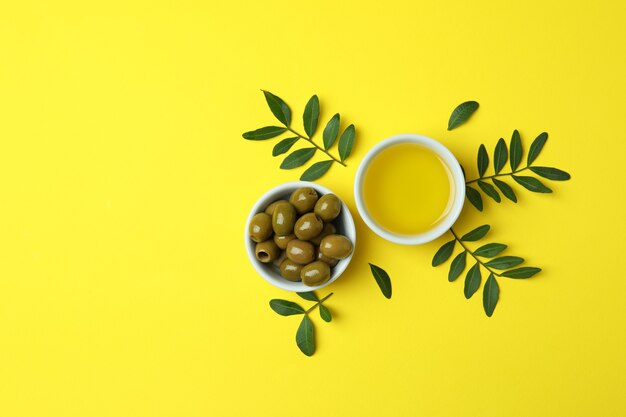 Bowls of oil and olives, and twigs on yellow surface