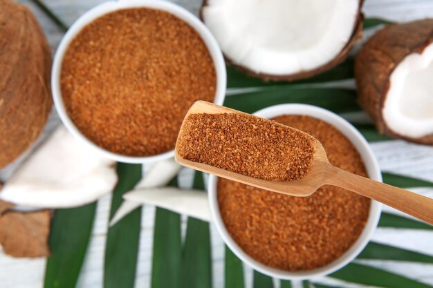 Foto ciotole e cucchiaio di zucchero di cocco su sfondo di legno