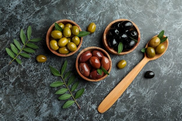 Bowls and spoon with olives on black smokey isolated background