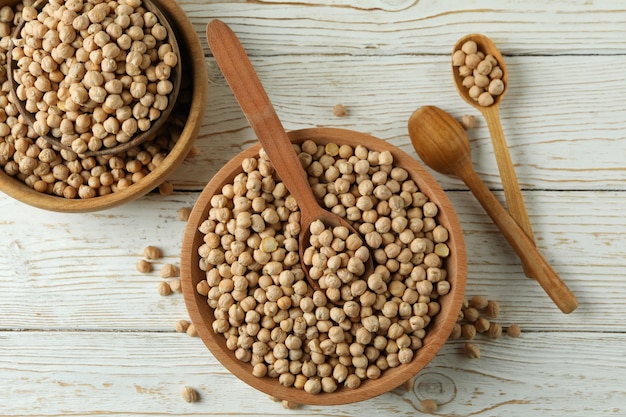 Bowls and spoons with chickpea on white wooden table