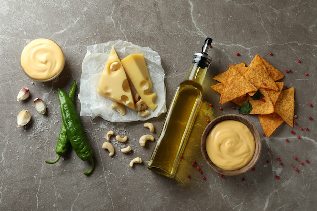 Bowls with cheese sauce and ingredients on gray textured table