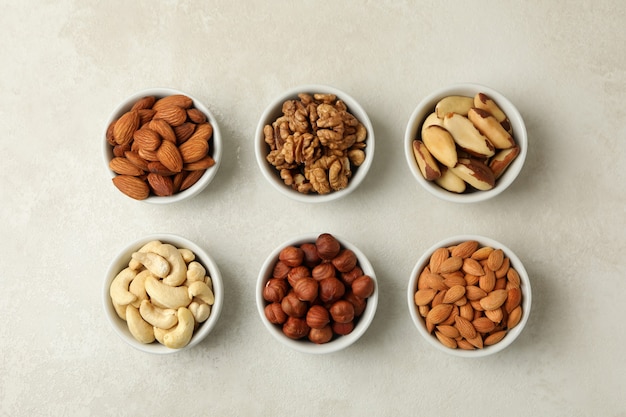 Bowls with different nuts on white textured