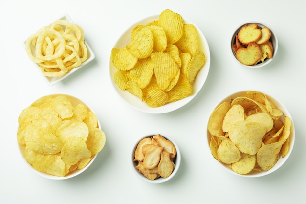 Bowls with different snacks on white surface