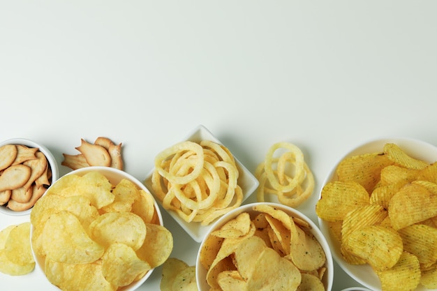 Bowls with different snacks on white surface