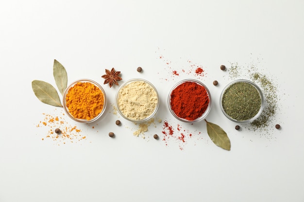 Bowls with different spices on white, top view