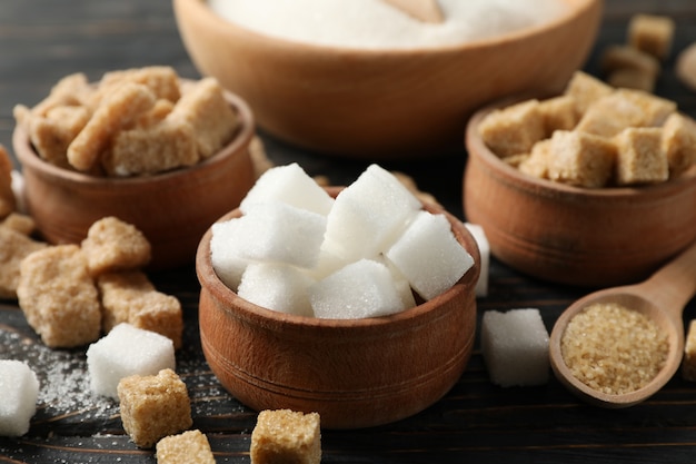 Bowls with different sugar on wooden background, close up