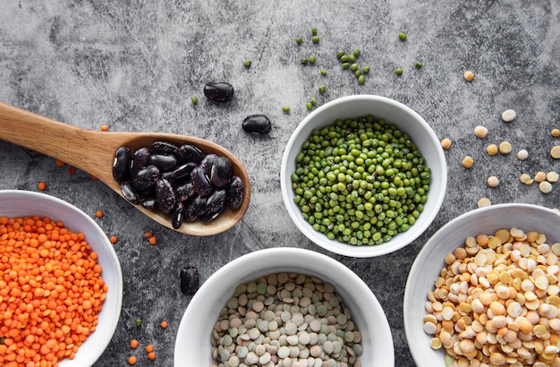 Bowls with different types of legumes on a gray concrete background