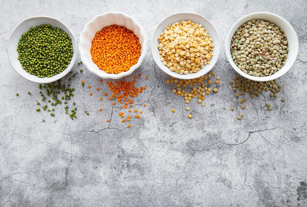 Photo bowls with different types of legumes on a gray concrete surface