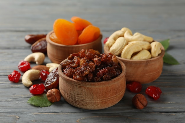 Bowls with dried fruits and nuts on gray wooden table