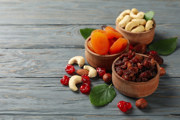 Bowls with dried fruits and nuts on gray wooden table