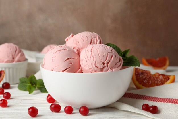 Bowls with ice cream balls on white wooden table